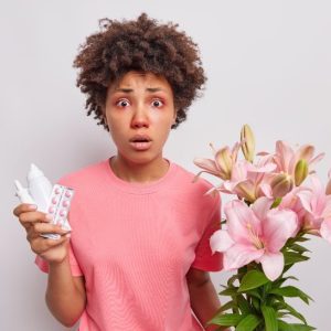 Lady holding flowers, suffering from hayfever with runny nose