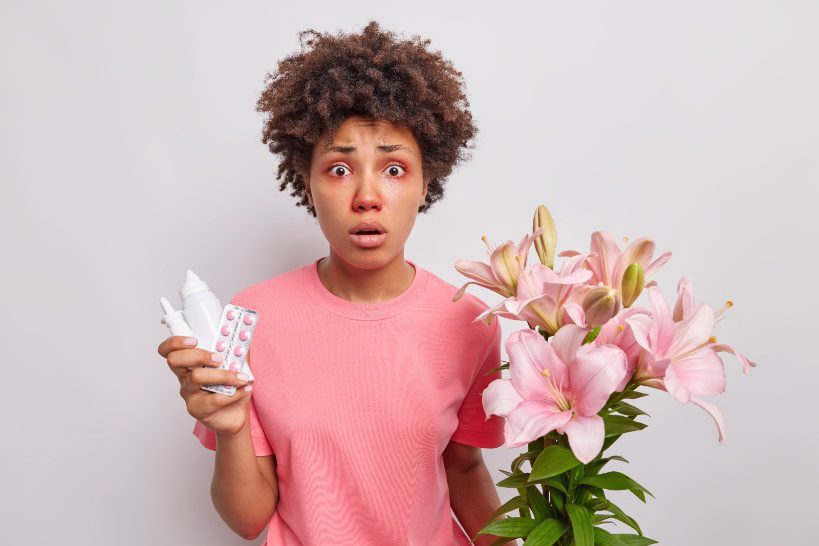 Lady holding flowers, suffering from hayfever with runny nose